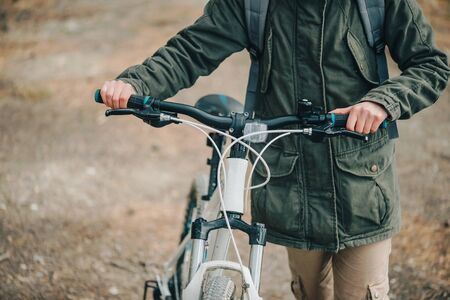 Hiker woman walking with bicycle in the forest, close-up