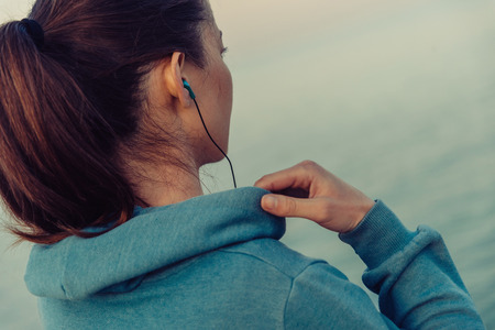 Sportswoman in headphones workout on coast in summer in the morning