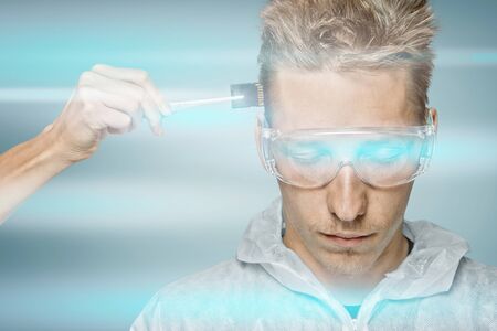 Human hand inserting a memory card in head of young man or robot, cyber space lighting, concept of...