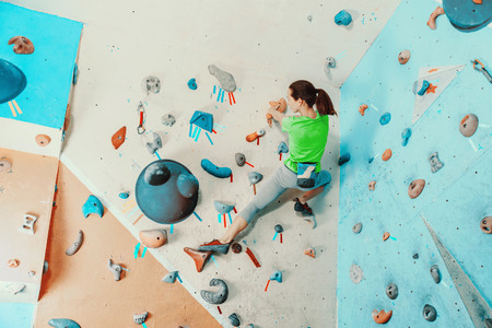 Sporty young woman exercising in a colorful climbing gymの写真素材