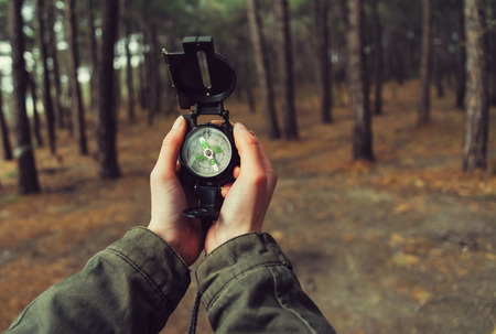 Hiker woman holding a compass in the forest. View of hands. Point of view shotの写真素材
