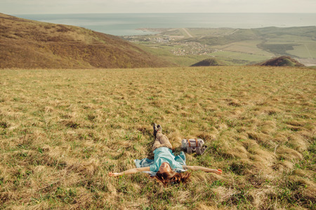 Happy hiker young woman lying on summer meadow in the mountainsの写真素材