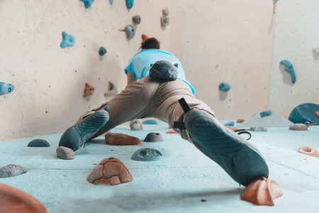 Sporty young woman climbing in gym, view from belowの写真素材