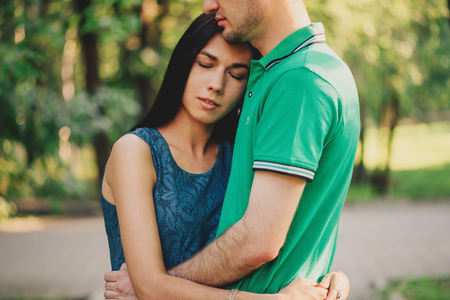 Young beautiful woman and young man embracing each other in summer park, tender scene. Couple in loveの写真素材