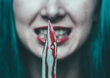 Spooky dangerous woman with knife in blood. Halloween or horror themeの写真素材