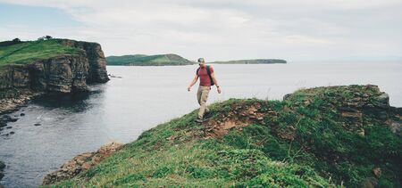 Hiker young man walking on coastline near the sea in summerの写真素材