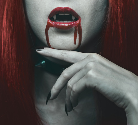 Beautiful vampire woman, close-up red lips in blood. Halloween or horror themeの写真素材