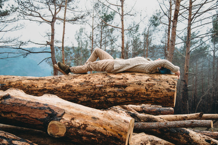 Beautiful young woman with blue hair lying on fallen tree trunk. Girl resting outdoorの写真素材
