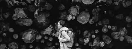 Hiker young woman with backpack walking on background of tree trunk. Black and white imageの写真素材