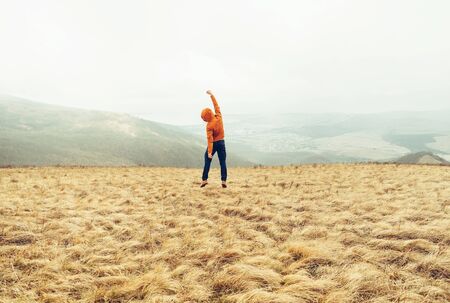 Happy young man jumping on meadow in the mountains