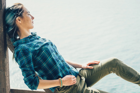 Beautiful young woman resting on coast and enjoying view of seaの写真素材