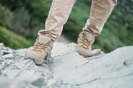 Female hiker walking on rocks outdoor, view of legs