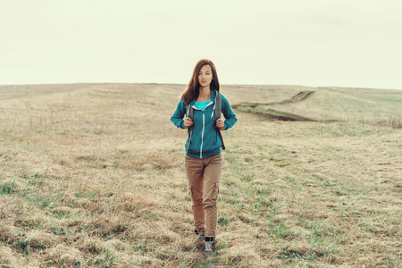 Explorer young woman walking on field in autumnの写真素材