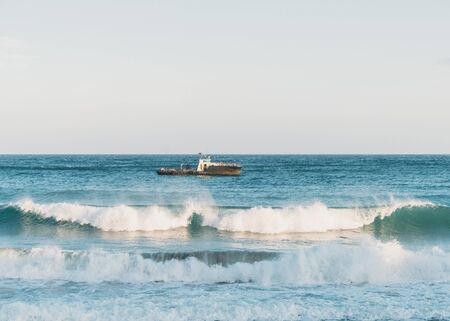 Boat in the sea at windy weather, sea waves with foamの写真素材