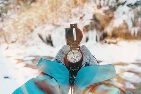 Unrecognizable traveler searching direction with a compass in winter, point of view shot. Image with sunlight effect.の写真素材