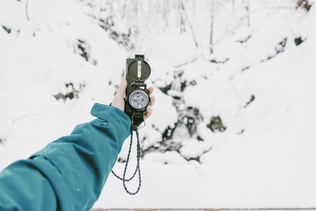 Unrecognizable female traveler searching direction with a compass in winter, point of view shot.の写真素材