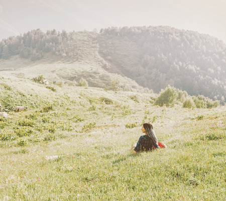 Young woman is resting on summer mountain meadow in sunny day.の写真素材