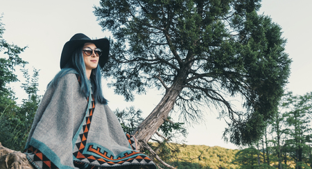 Smiling beautiful young woman resting on tree in spring park.の写真素材