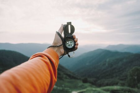 Man explorer searching direction with compass in summer mountains, point of view.の写真素材