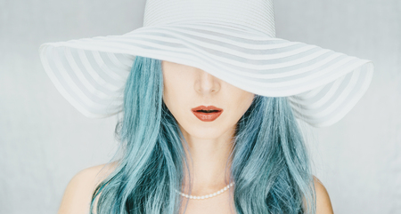 Young woman with blue hair in a hat with wide brim, fashion and beauty.の写真素材