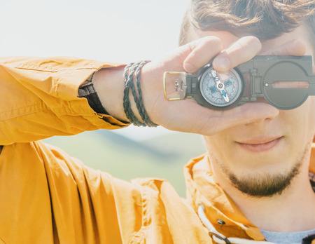 Smiling explorer traveler young man holding compass outdoor in summer.