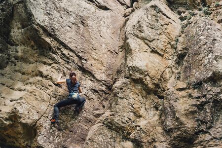 Sporty young woman free climbing on rock outdoor.の写真素材