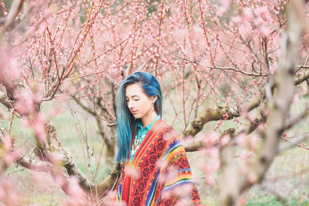 Boho style young woman walking in pink flowering peach tree gardenの写真素材