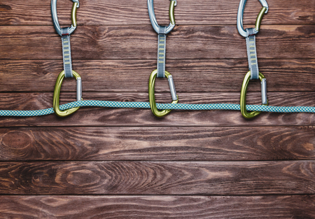 Rope with quickdraws on a wooden background, top view. Copy-space in lower part of the image.