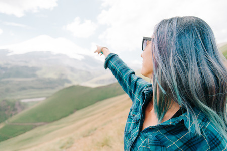 Explorer young woman pointing at snowy high mountain outdoor.の写真素材