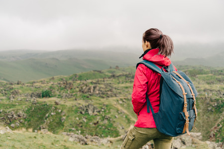 Explorer young woman with backpack walking in summer mountains.の写真素材