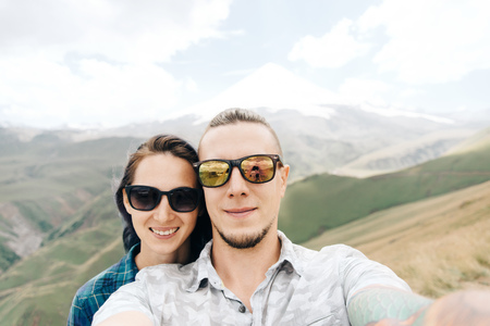 Happy young loving couple taking selfie in the mountains, point of view.の写真素材
