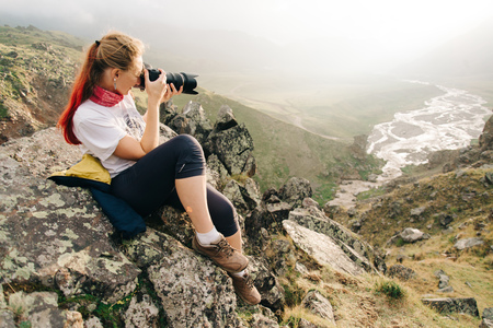 Woman traveler photographs mountain landscape.  Wide-angle shotの写真素材