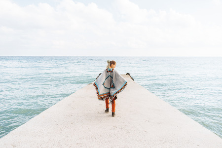 Beautiful boho style woman walking on sea pier.の写真素材