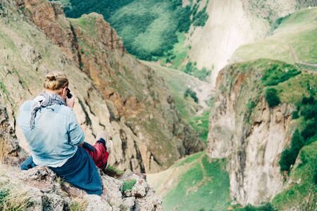Traveler photographer young man sitting high in the mountains.