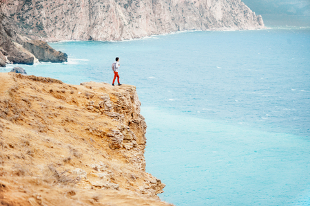 Backpacker traveler young woman standing on edge of cliff over sea.の写真素材