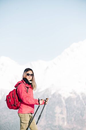 Hiker young woman with trekking poles walking in winter outdoor.の写真素材