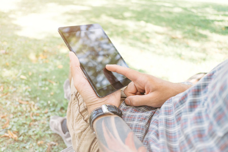 Close-up image of male hands with digital tablet in the park.の写真素材