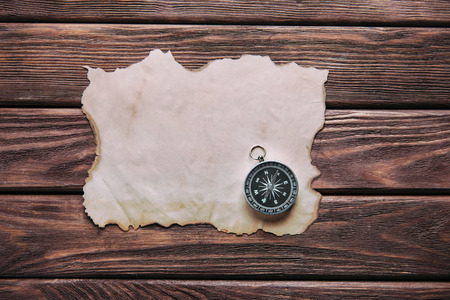 Compass and blank old paper on a wooden background, top view, copy-space.の写真素材