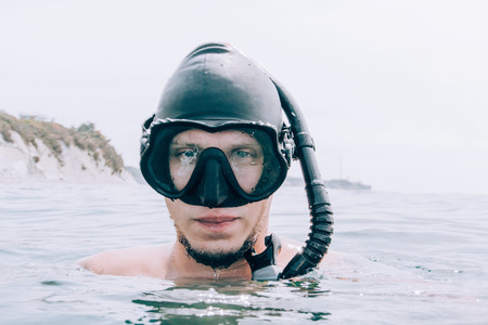 Portrait of young man freediver in mask and with snorkel above sea surface.の写真素材