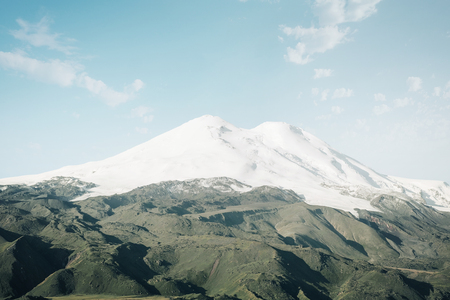Mount Elbrus with snowy peaks and green fields on sunny day, Caucasus mountain range, Russia.の写真素材