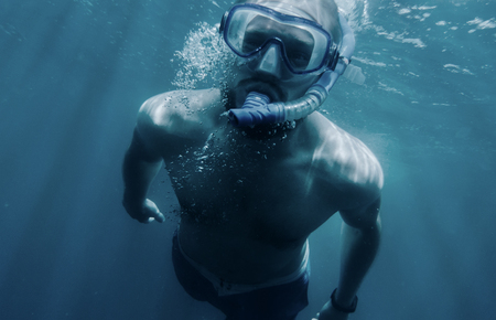 Active young man freediver in mask with snorkel swimming underwater.の写真素材