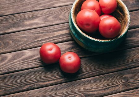 Fresh red ripe tomatoes in a bowl on a wooden table.の写真素材