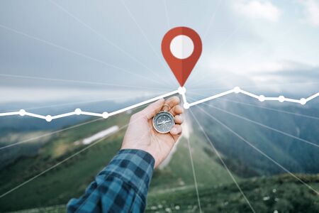 Male hand with magnetic compass and GPS route with location pin in summer mountains outdoor, point of view. Navigation concept.の写真素材