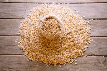 Oatmeal flakes in a sack on a wooden background, top viewの写真素材