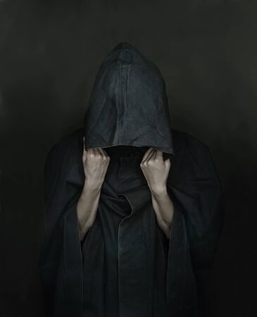 Unrecognizable human in black coat with a hood, face is not visibleの写真素材