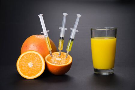 Syringes pumped out vitamins from an orange to juiceの写真素材