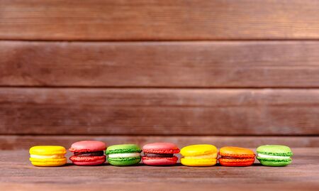 Colorful sweet macarons dessert in a row on wooden table. Copy-space in upper part of image.の写真素材