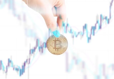 Womanâs hand with gold coin bitcoin on background of growth infographic.の写真素材