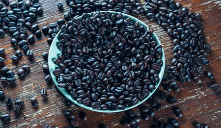 Roasted coffee beans on a saucer on a wooden backgroundの写真素材