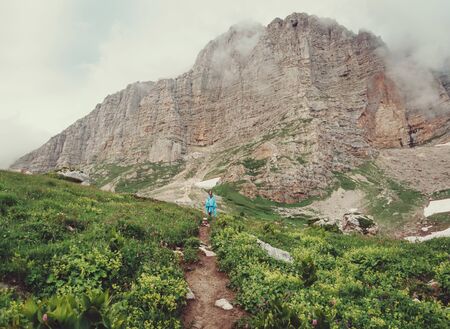 Explorer young woman wearing in raincoat walking near the cliff, Caucasus, Russiaの写真素材